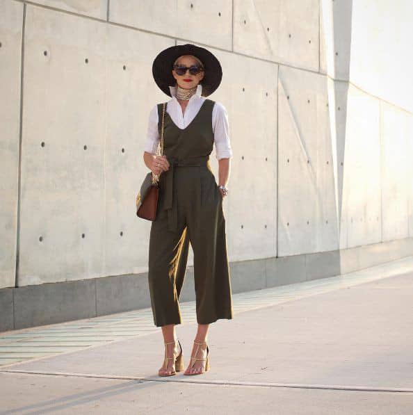 lady wearing jumpsuit on white shirt, hat and glasses