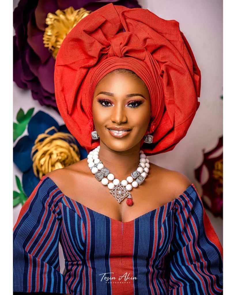 smiling lady wearing dark orange gele
