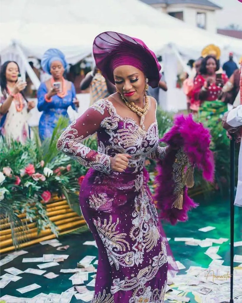 beautiful lady dancing in a purple gele and asoebi dress
