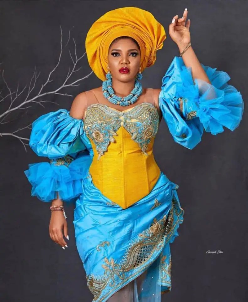 lady wearing yellow gele with blue asoebi outfit