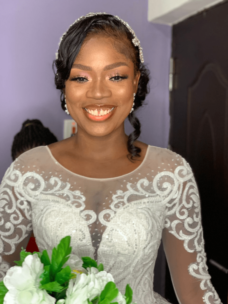 smiling bride wearing make up for her white wedding