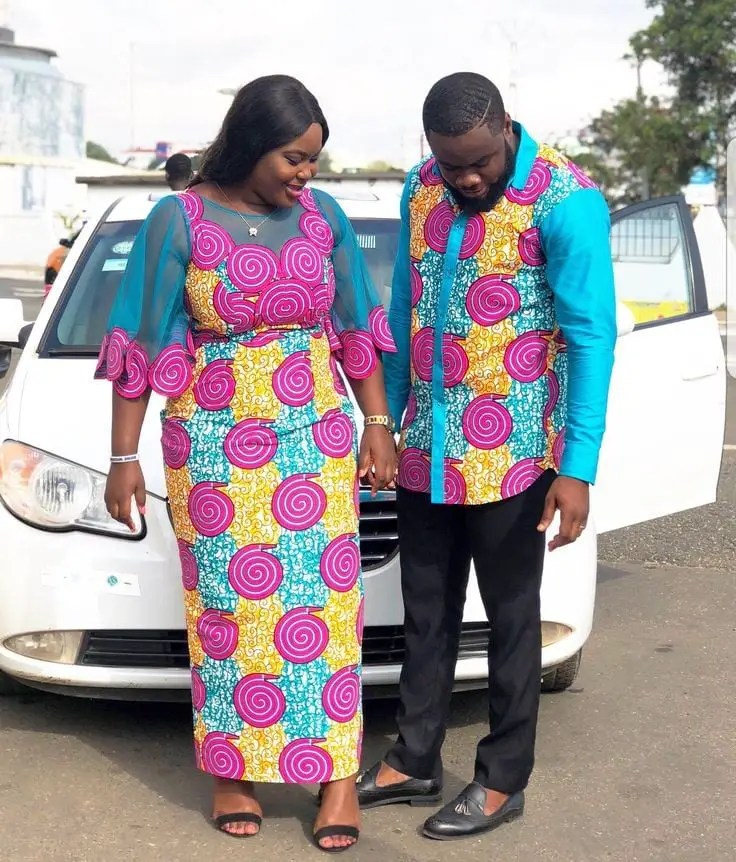 man and wife rocking matching ankara outfits, posing in front of a car