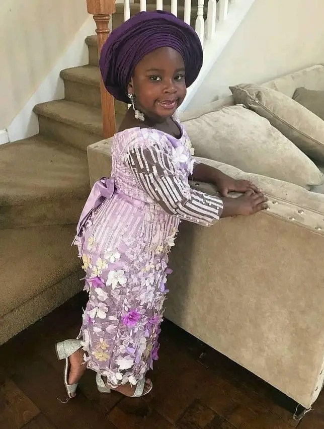 smiling little girl wearing white lace outfit with gele