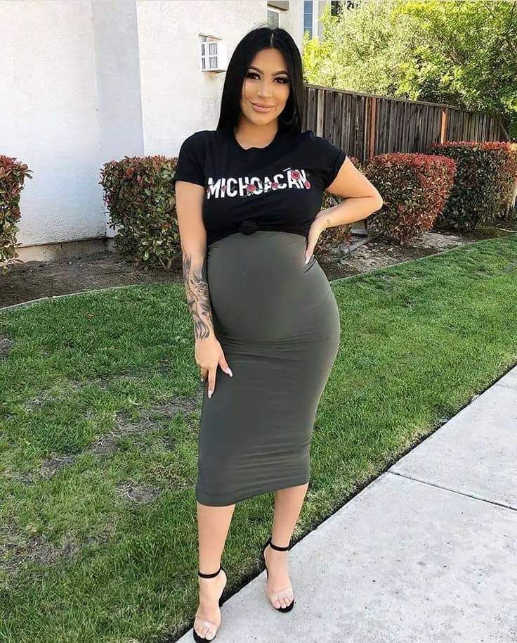 A smiling woman wearing a top and skirt during pregnancy