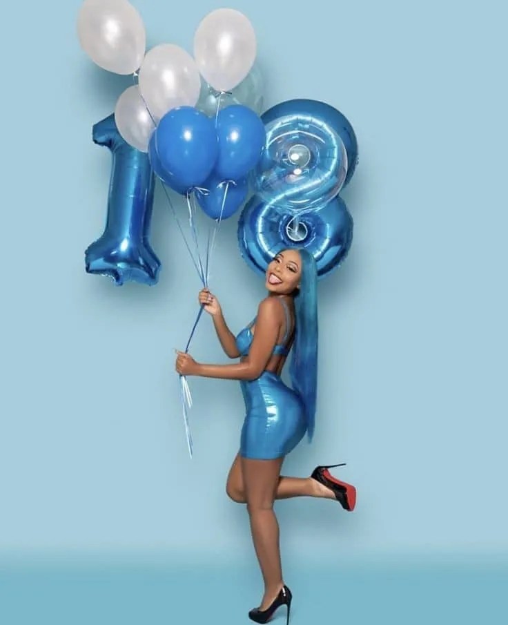 Happy woman holding balloons on her 18th birthday