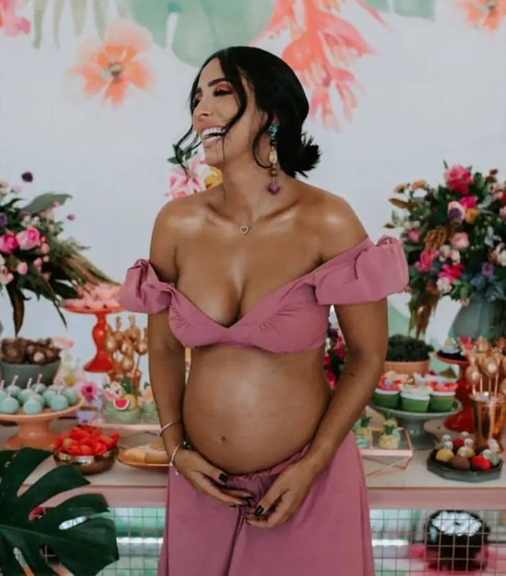 lady wearing crop top and skirt showing baby bump