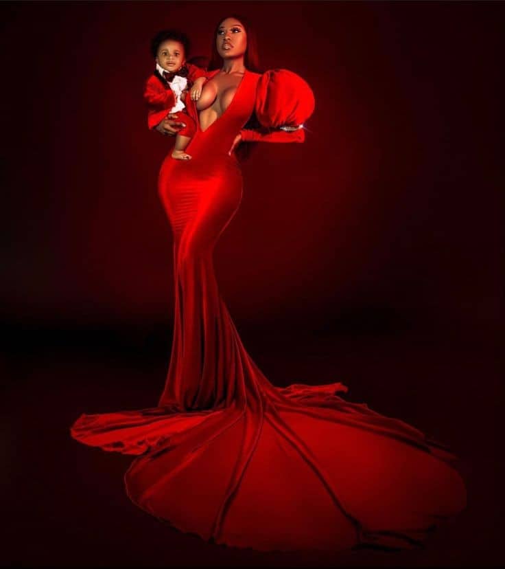 lady wearing a red long dress and carrying a child