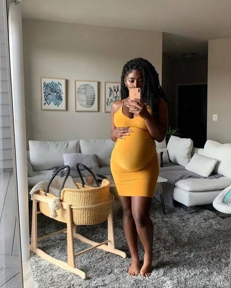 Pregnant woman wearing a fitted orange dress