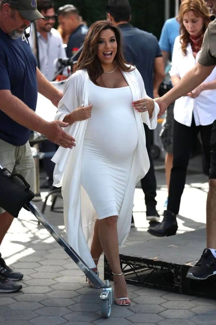 Pregnant woman wearing a white gown on the street