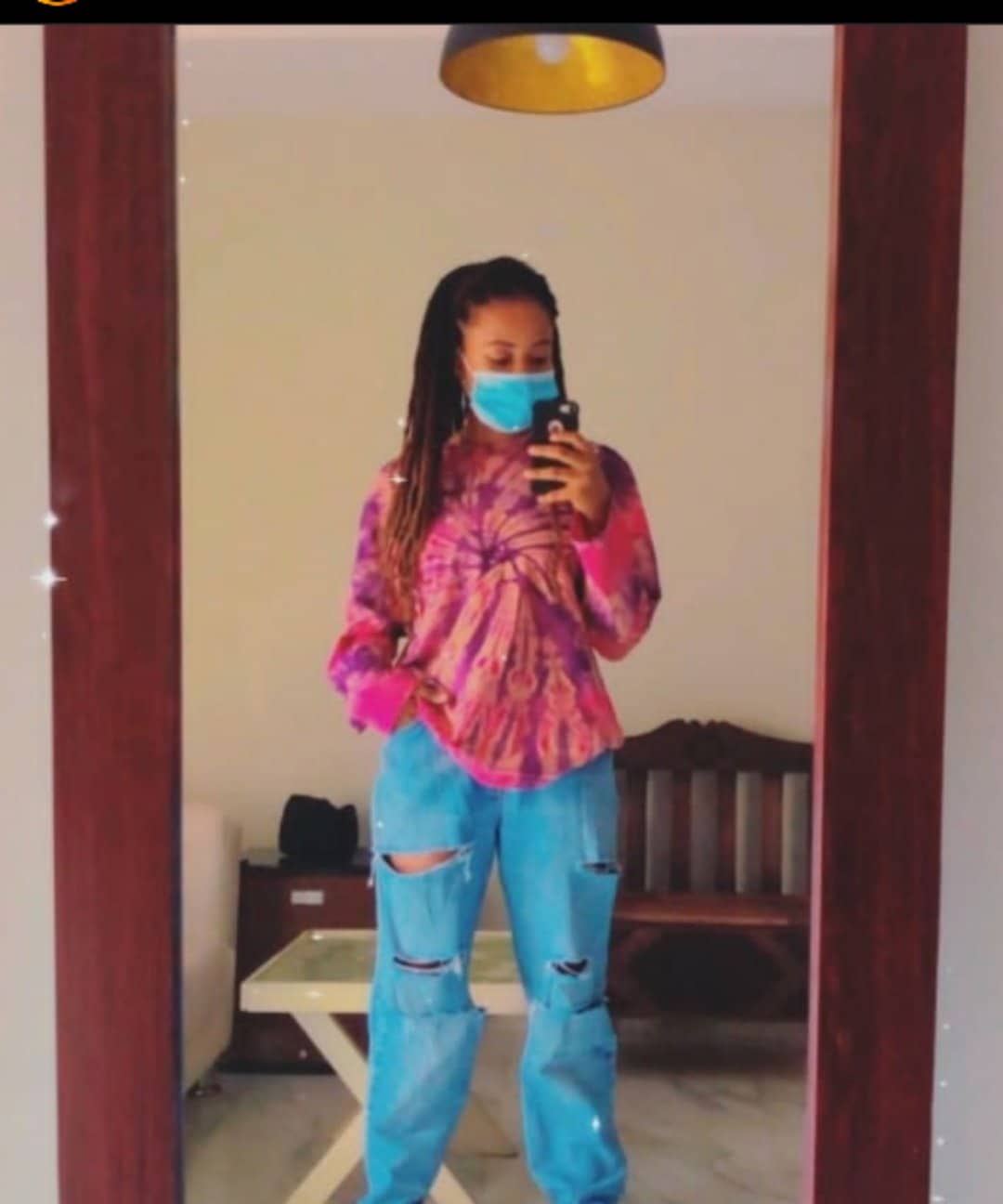 lady wearing adire top with ripped jeans