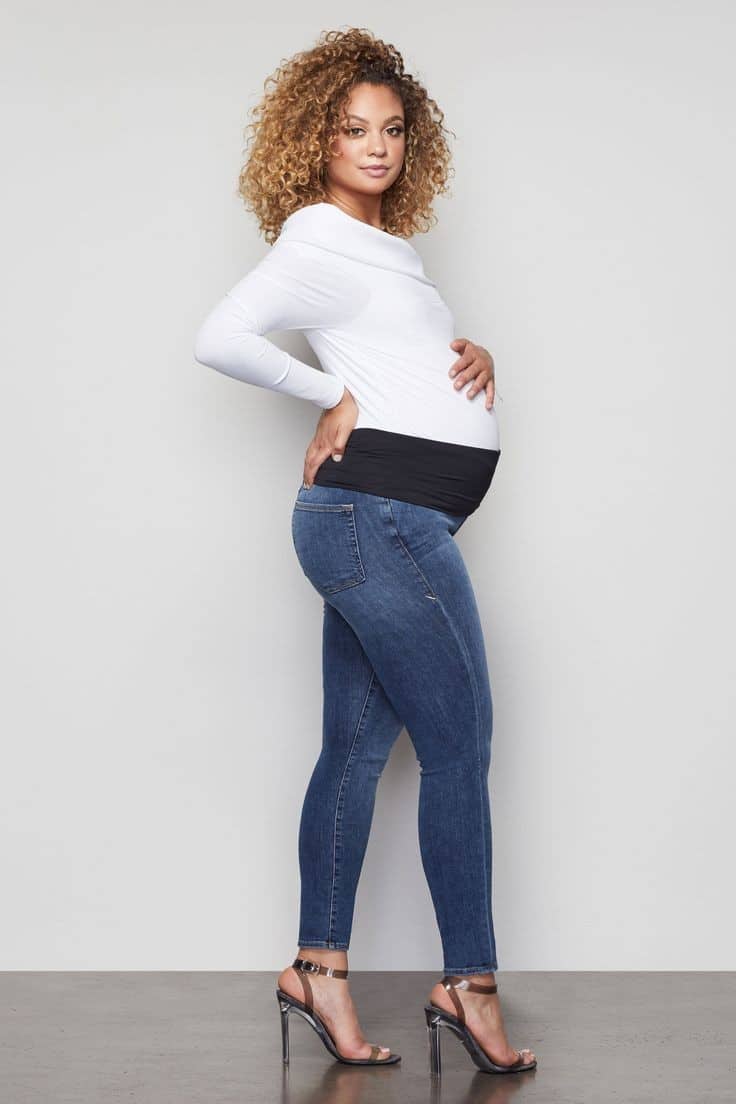 Pregnant woman wearing maternity jeans and white top