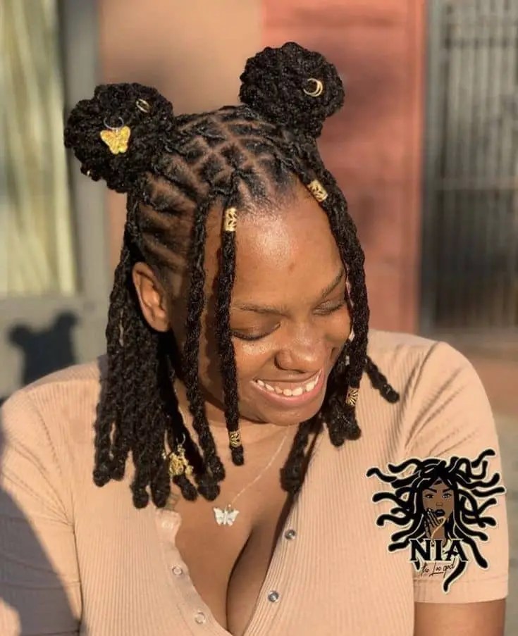 A smiling woman wearing a Senegalese braid with two bumps