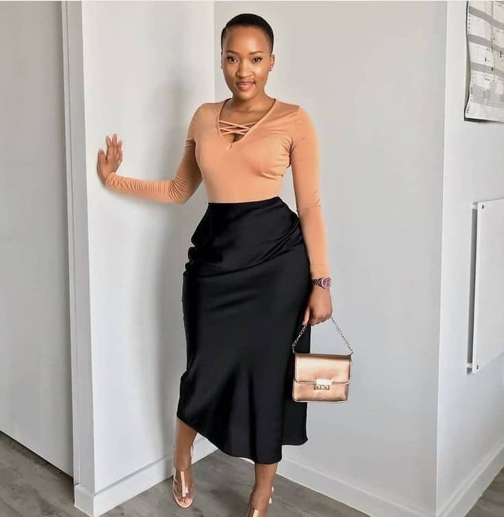 A woman wearing a top and a black midi skirt for a birthday party
