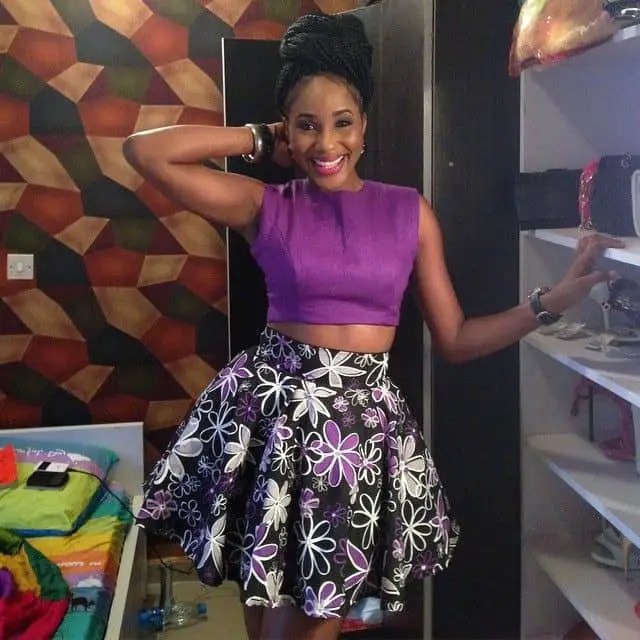 A smiling woman wearing a short flared skirt and a purple top