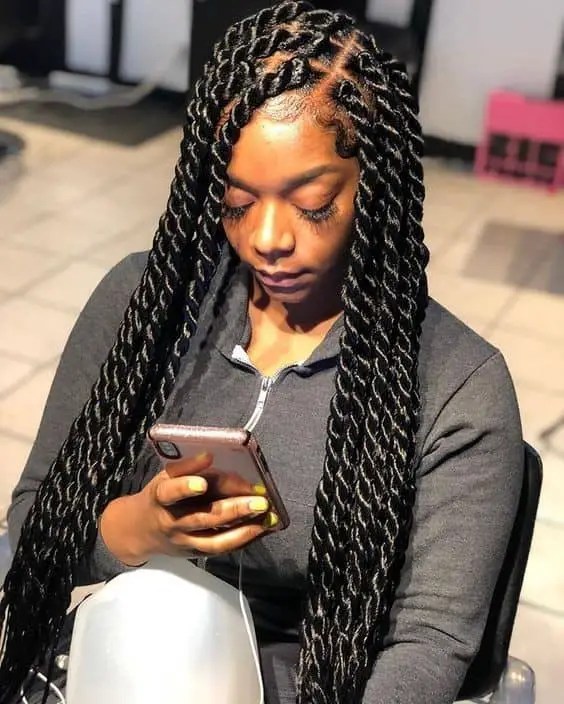 A woman wearing a long Senegalese braid and predicting a phone call