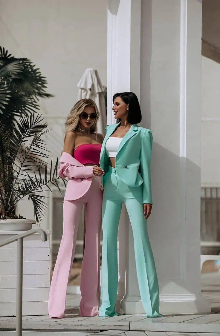 Two women wearing different light-colored pant suits
