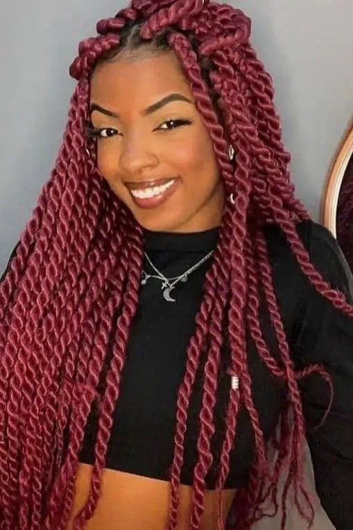 A smiling woman wearing a long red Senegalese twist