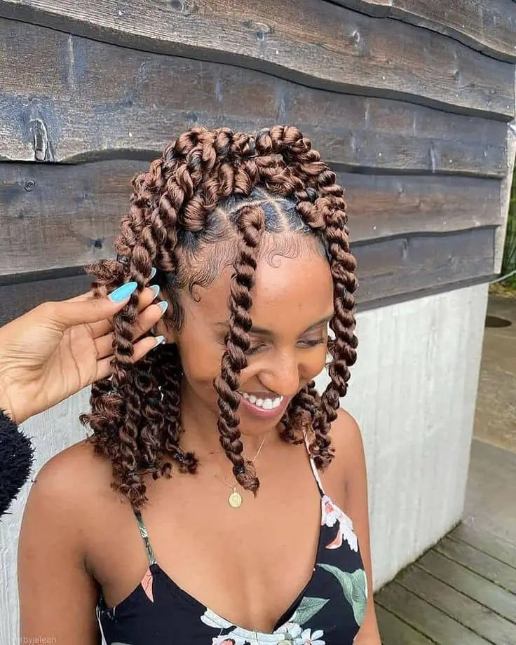 A smiling woman wearing a shoulder-length Senegalese twist