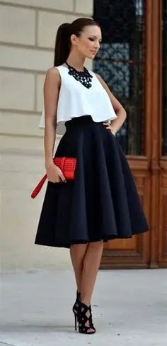 Woman wearing a black flared skirt and a white crop top