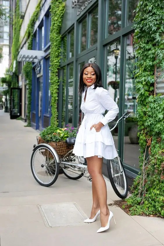 smiling woman wearing little white dress with white heels