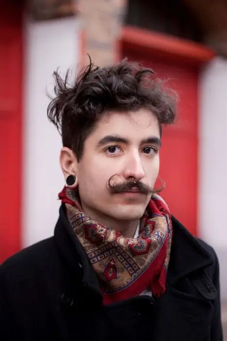 Man with handlebar mustache style tying scarf