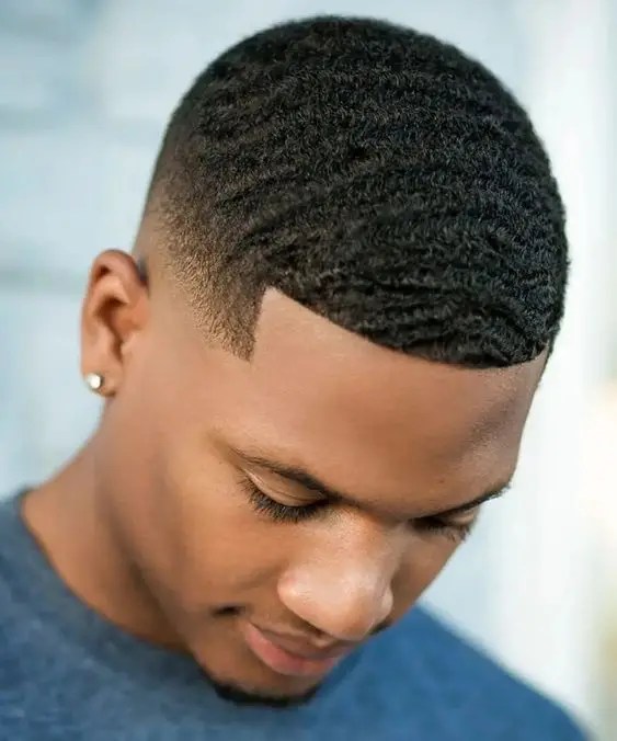 A man with short hair and wearing a wavy fade