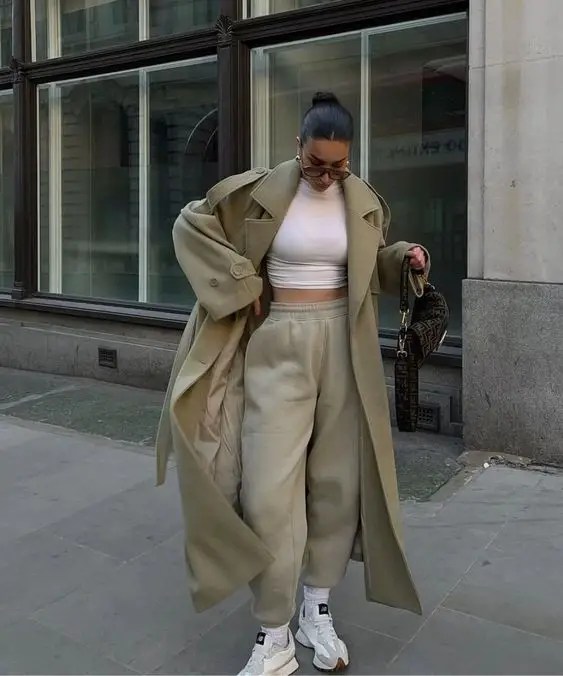 A woman wearing a long coat over jogger pants