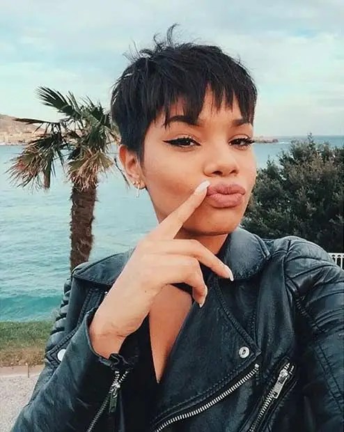 A woman wearing a messy pixie cut is taking a selfie