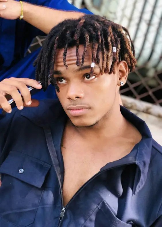 Man rocking black and brown short dreads style for men with silver cuff accessories