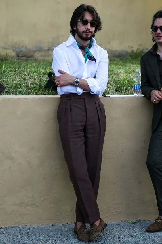 A man wearing dark brown high-waisted men's pants with a scarf around his neck