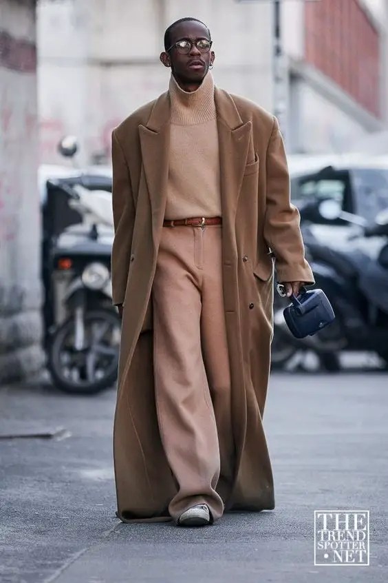 Man rocking high-waisted brown men's pants with brown turtleneck top and long brown coat