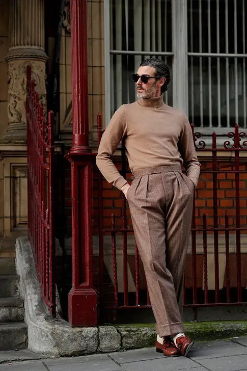 A man wearing a brown turtleneck top with brown high-waisted pants