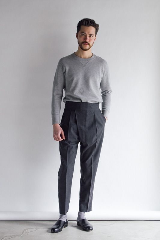 A man wearing men's high-waisted pants and an ash-colored long-sleeved T-shirt