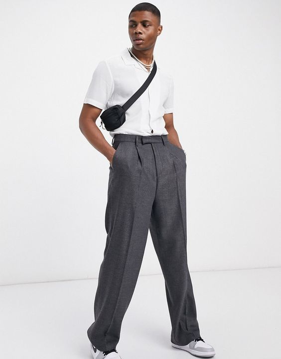 Man in high-rise pants, short-sleeved white shirt and carrying cross bag