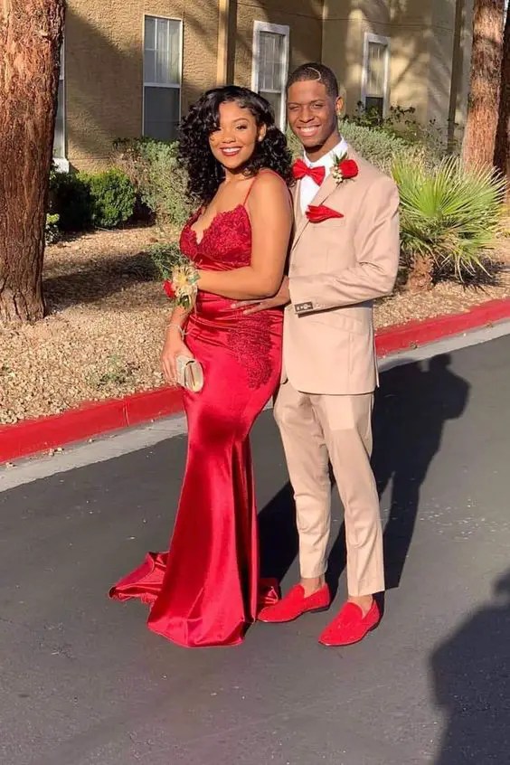 A woman in a red dress and a man in a light brown suit and red accessories