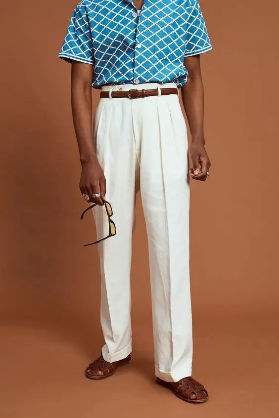 Man wearing men's white high-waisted pants and blue striped shirt and belt