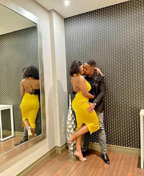 A woman in a yellow dress is holding a man in a black shirt