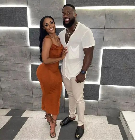 Man in white shirt and beige pants and woman in brown spaghetti strap midi dress