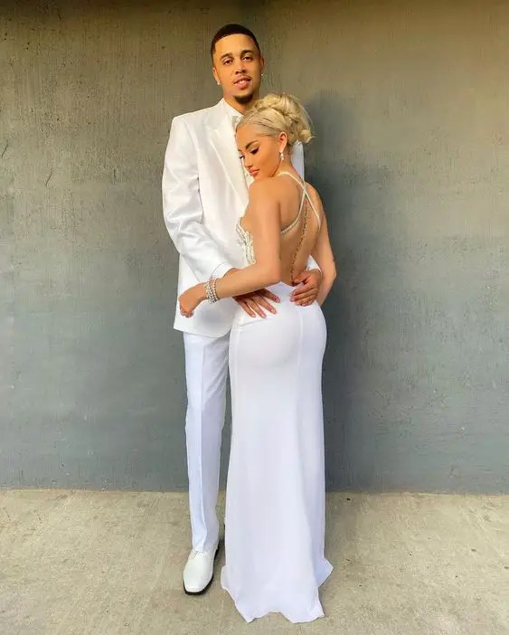 A man in a white suit holding a woman in a backless white dress