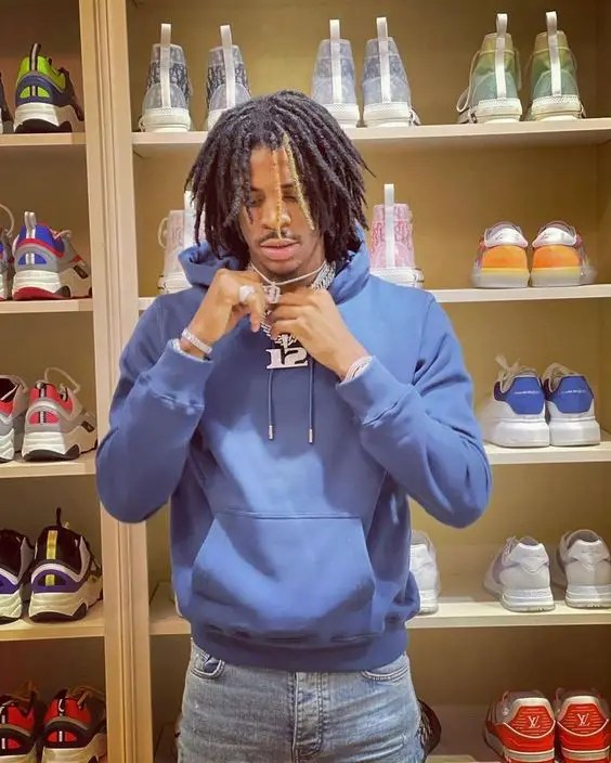 A man with full dreadlocks and wearing a blue hoodie