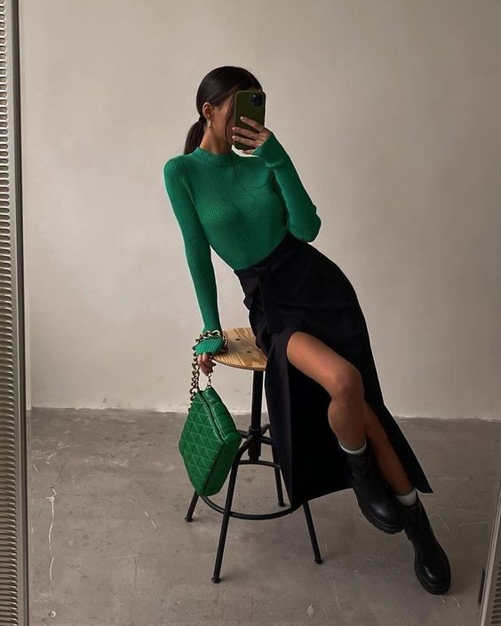 a lady wearing a black midi skirt with slit and a green top and green bag