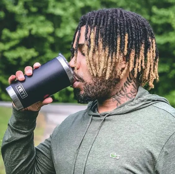 Man wearing ombre dreads and drinking from a cup