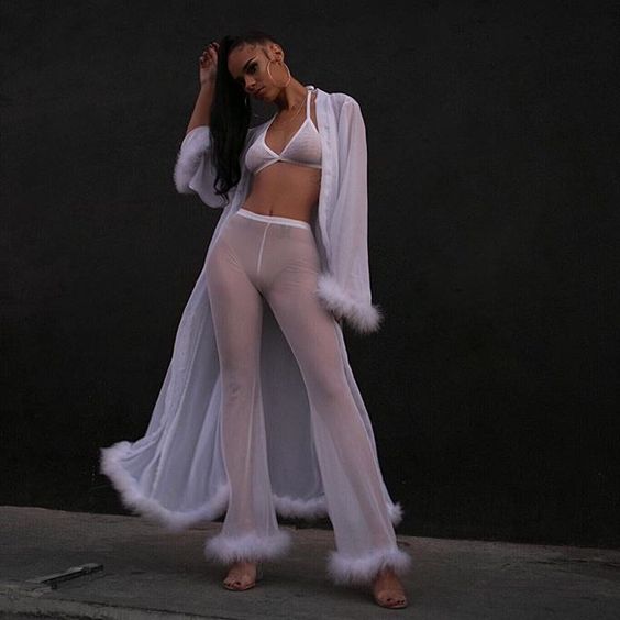 A woman wearing white thin pants and a bra top and a white kimono