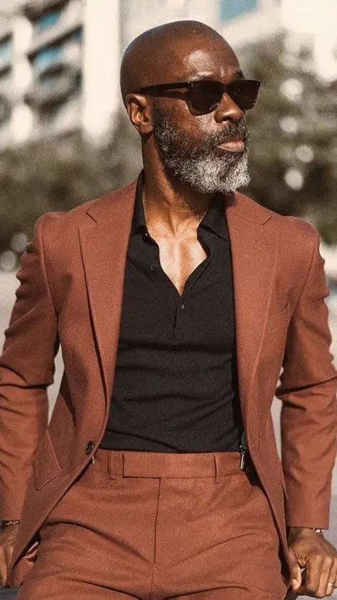 A man wearing a high-rise pantsuit, a jacket, and a black shirt