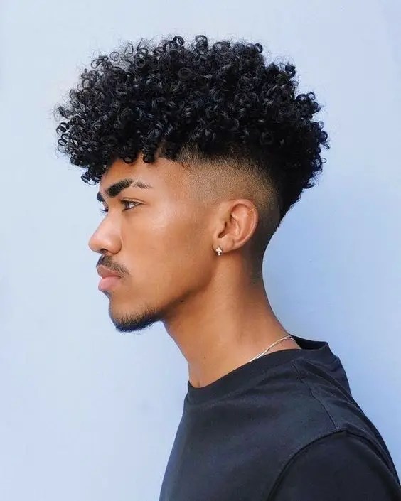 Man wearing studs showing off curly hairstyles for men
