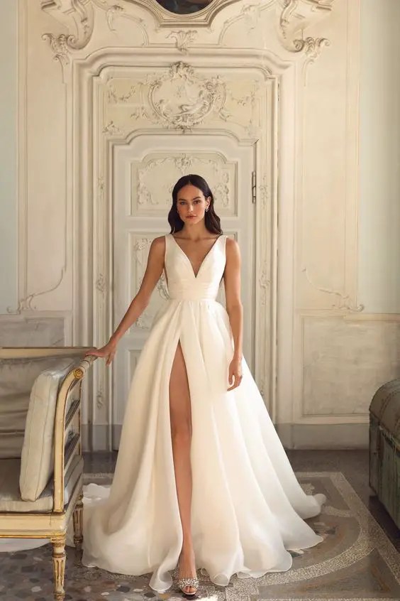 A woman wearing a sleeveless white maxi dress with a thigh-high slit like a casual wedding dress