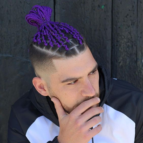 A man rocking his purple braid and holding his chin