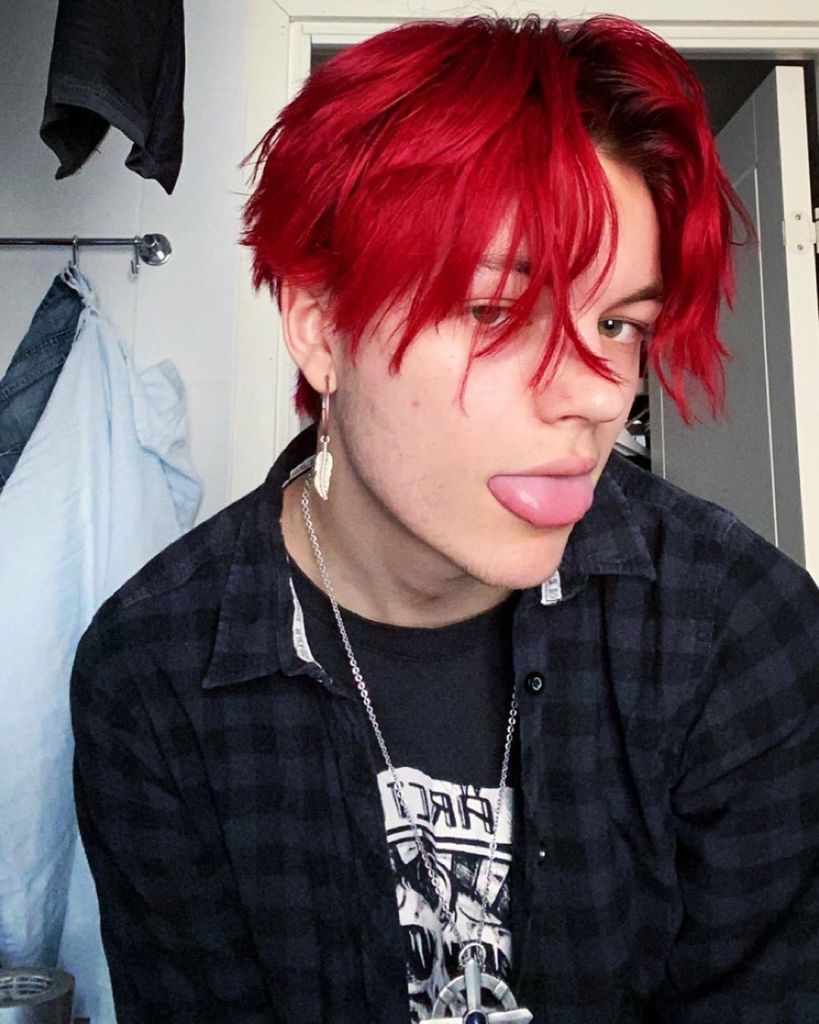 Man sticking out his tongue while wearing a red wolf cut
