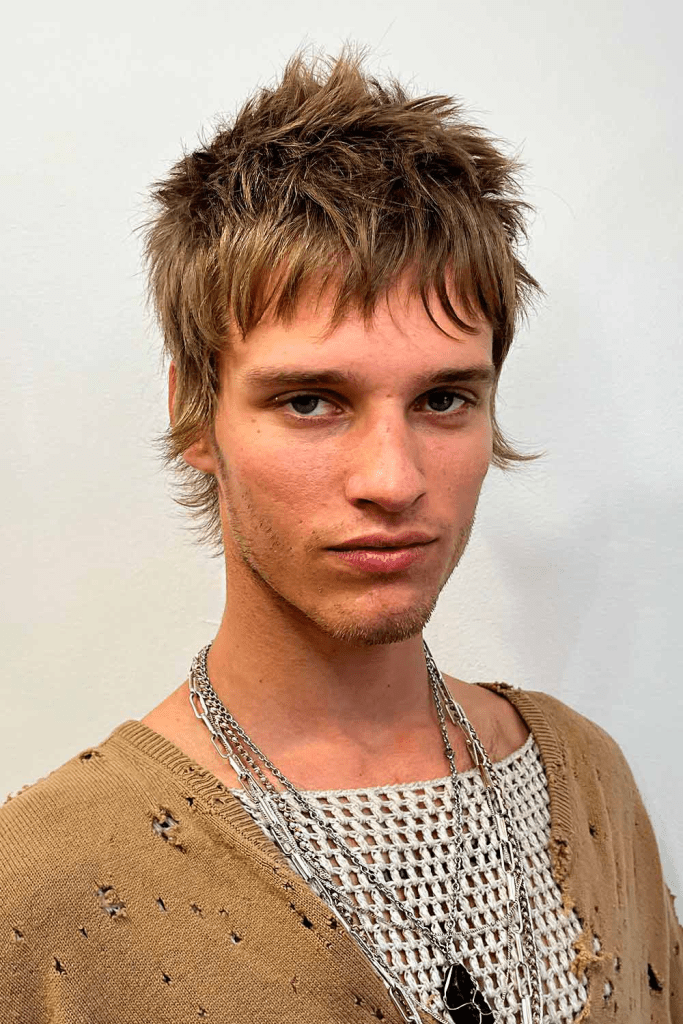 A man in a ragged top is rocking his hairy bangs