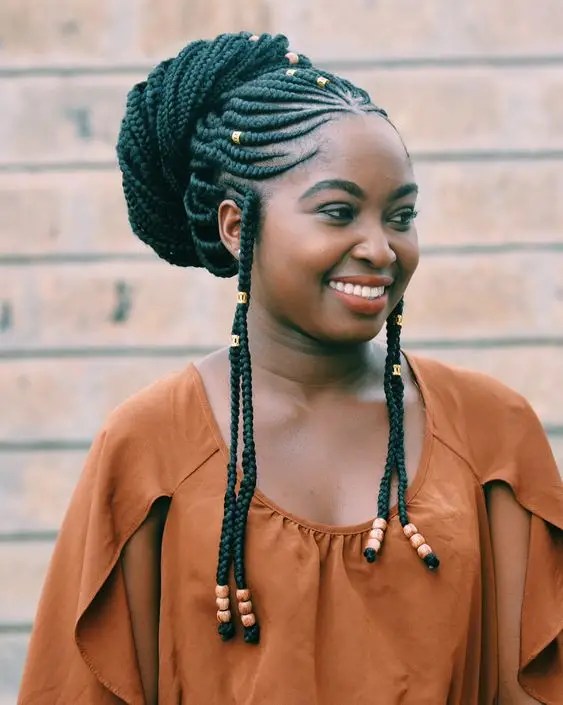 Beautiful smiling woman with rocking ghana braid wrapped in a bun and accessorized with beads